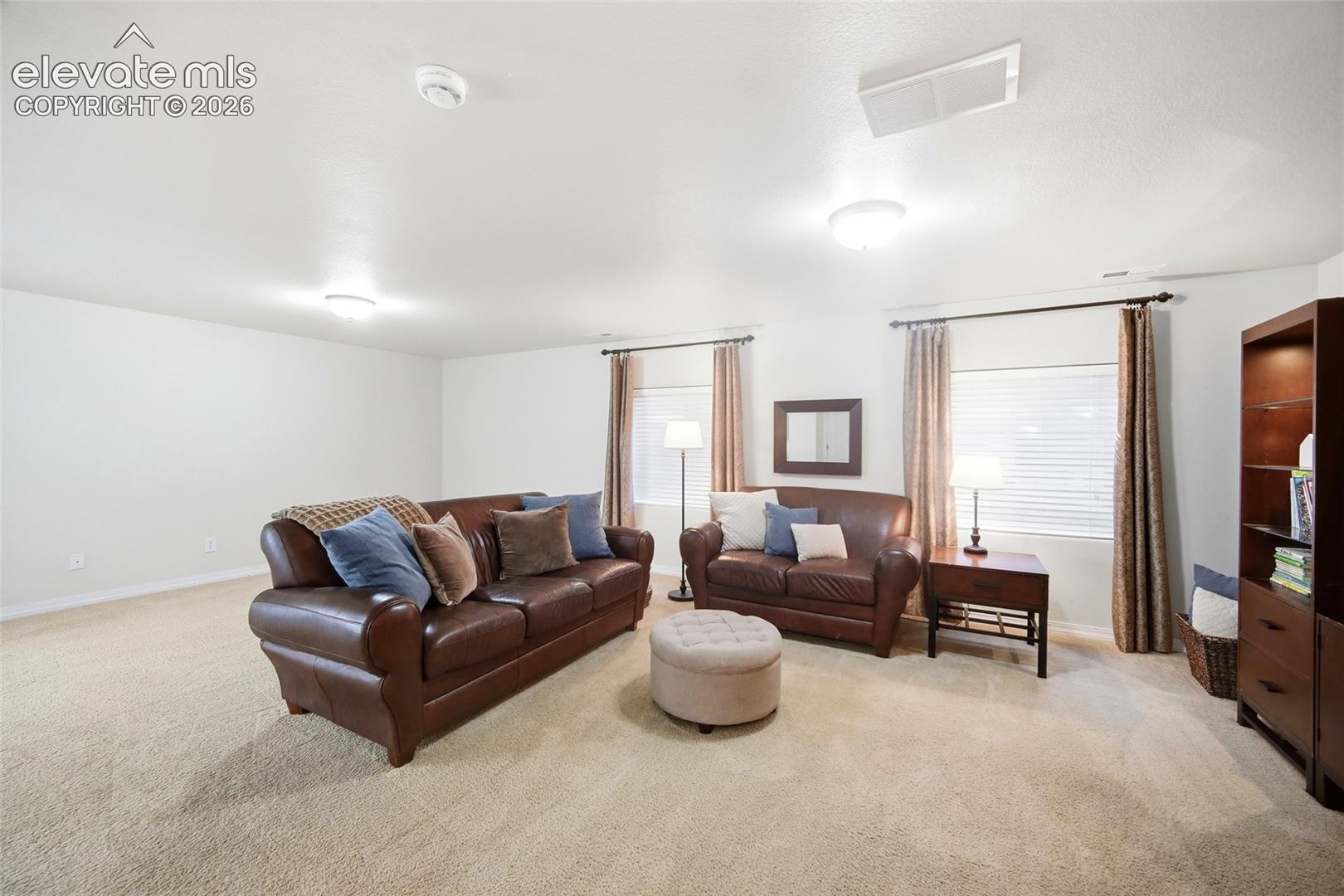 Recessed lighting, light beige carpeting, white walls, and window treatments with blinds