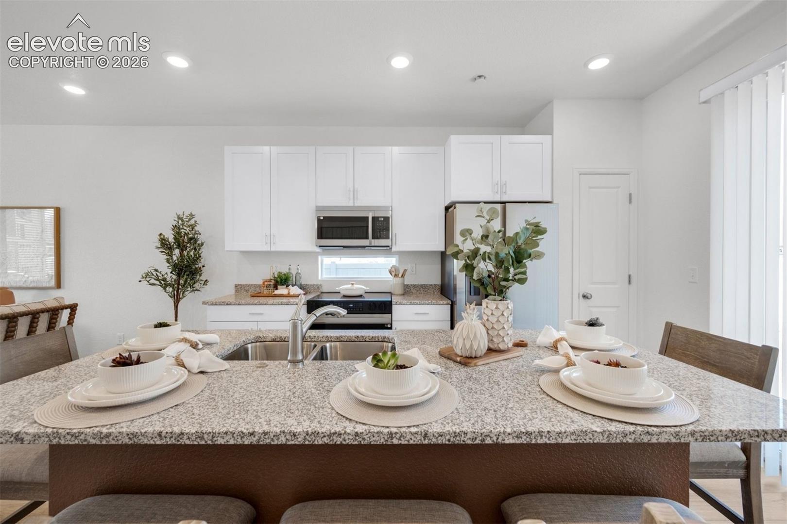 Kitchen featuring white cabinetry, stainless steel appliances, speckled countertops, a double basin sink, and recessed lighting
*photos of a model home*