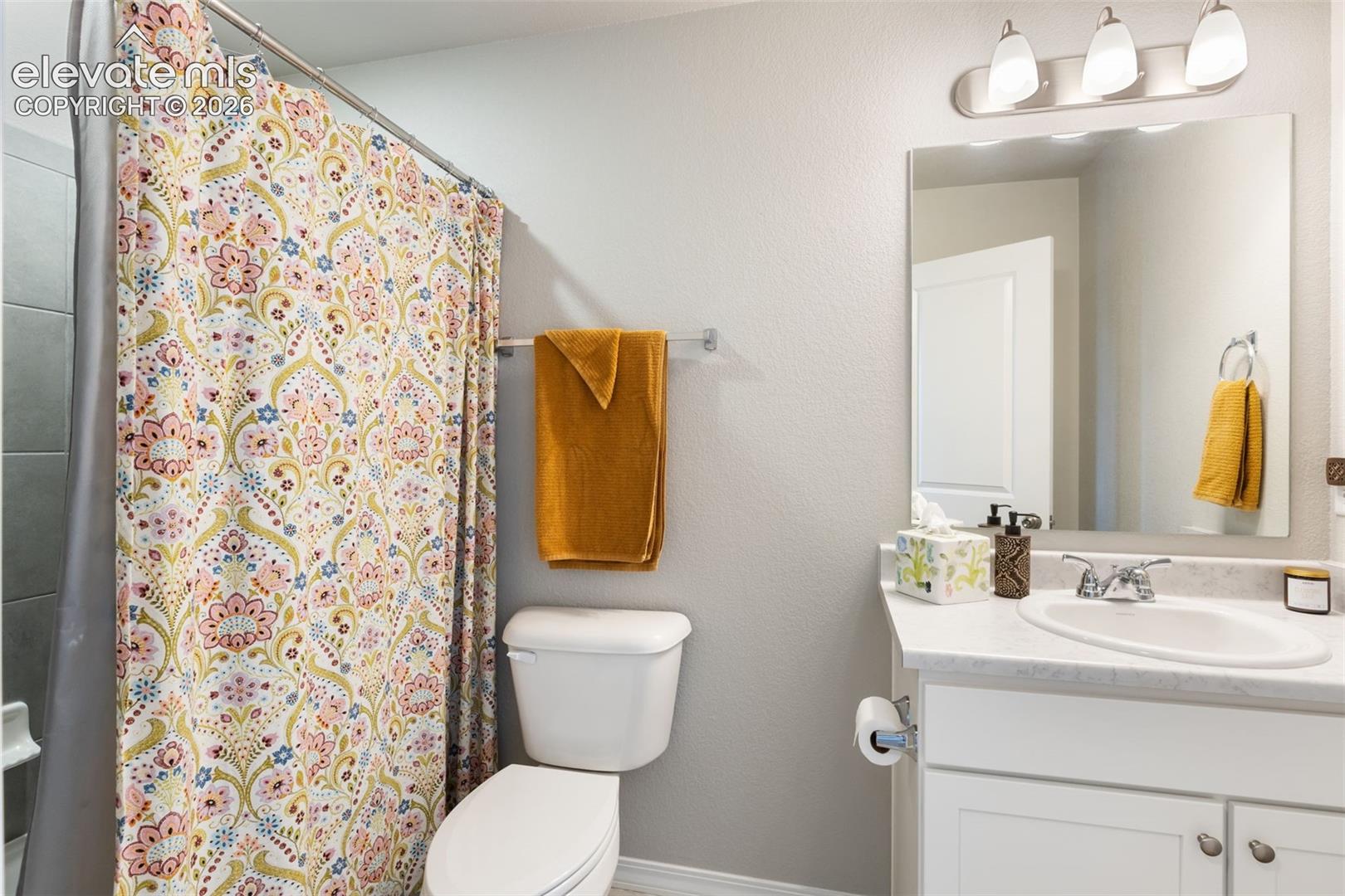 Bathroom featuring a single vanity with an integrated sink, polished chrome faucet, and overhead three-bulb light fixture