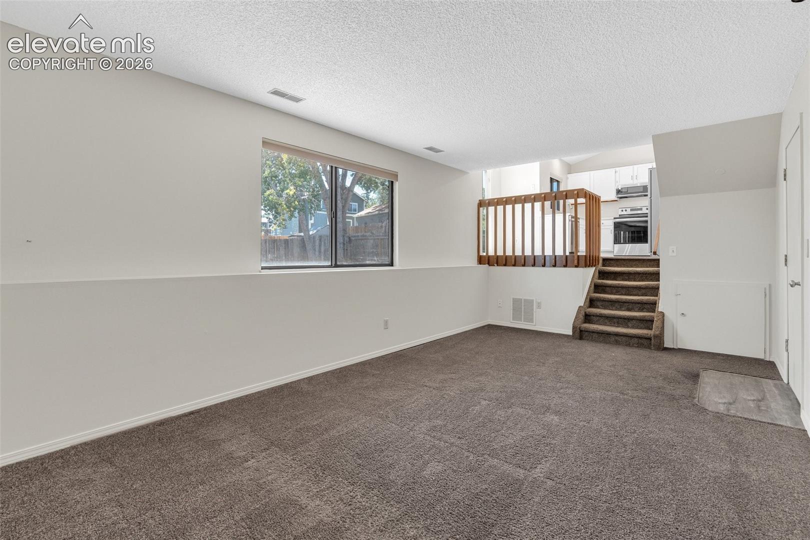 Recessed lighting, wood-finish stair railing, built-in shelving, full-size window, and wall-to-wall carpeting