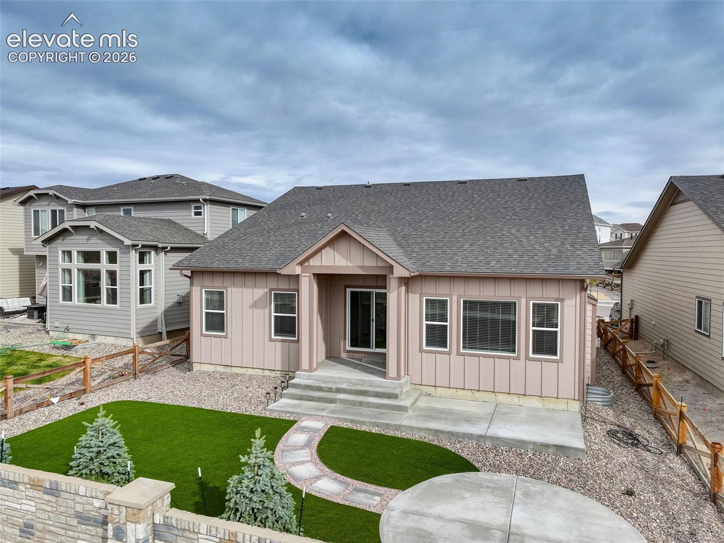 Rear exterior featuring a concrete patio, stone pathway, and artificial turf lawn