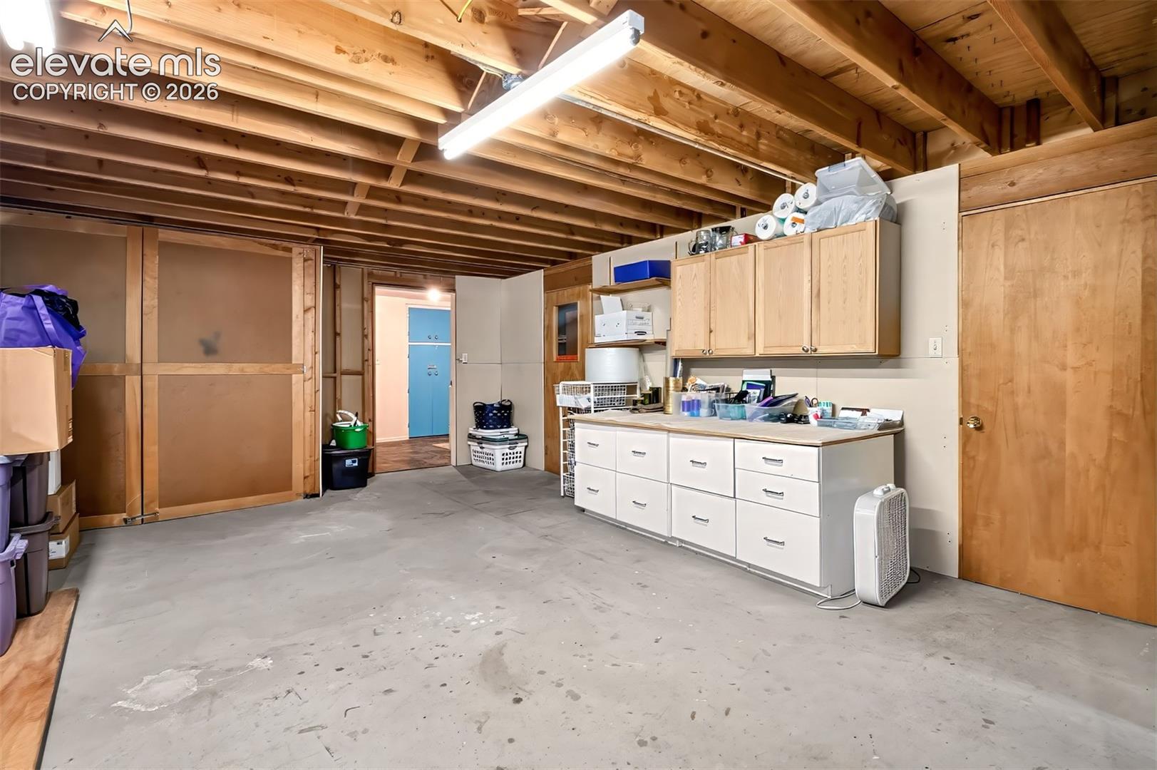 Off of the laundry area, this unfinished basement space is filled with storage and cabinetry