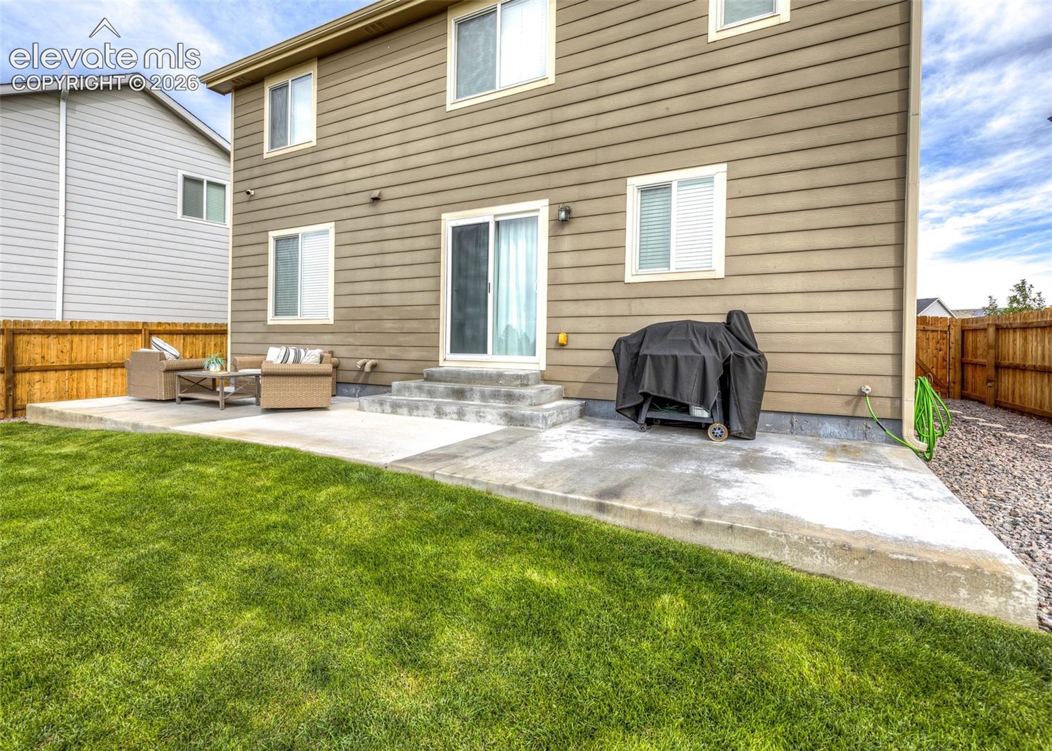 Horizontal siding exterior featuring a concrete patio, sliding glass door, and wooden perimeter fencing