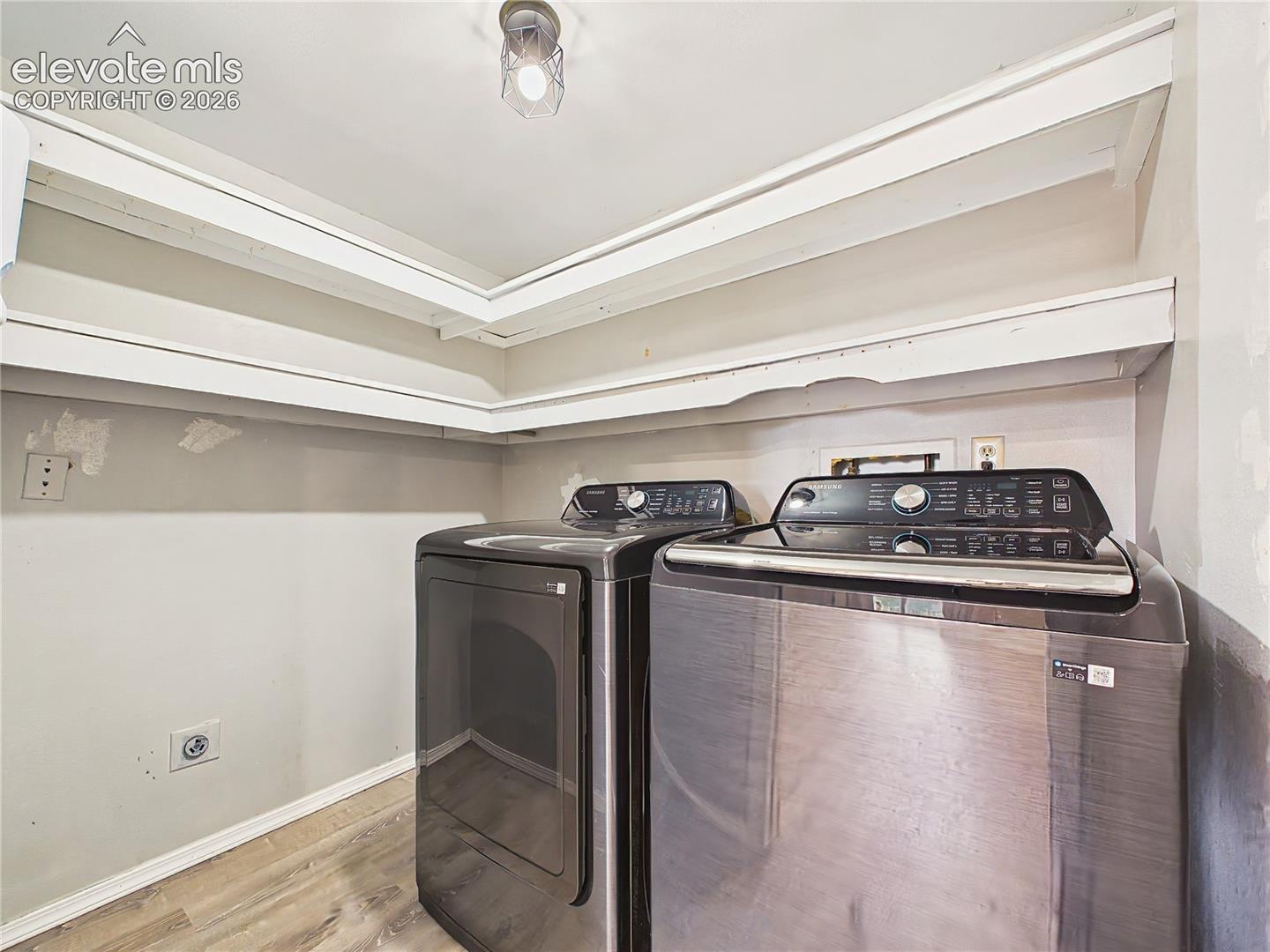 Convenient laundry room with built-in shelving for organized storage and space for full-size washer and dryer.