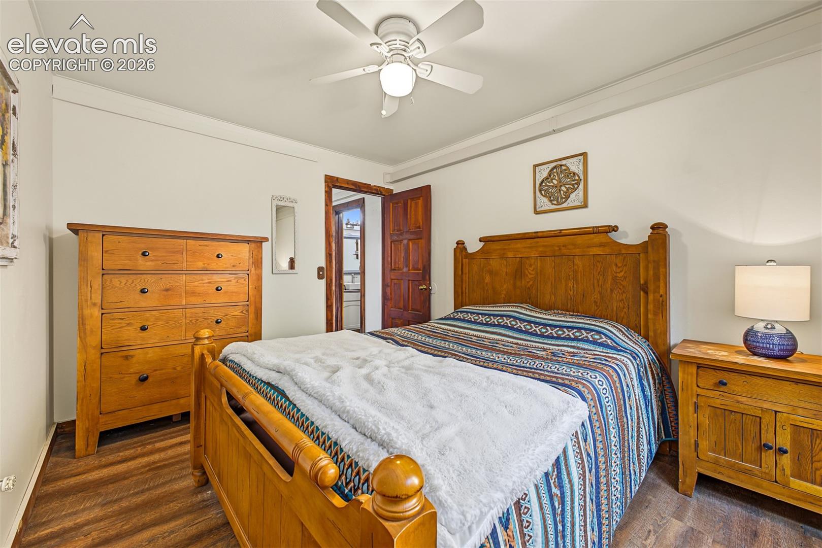 Wood-finish flooring with white walls and a ceiling fan