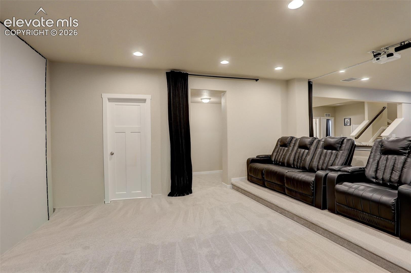 Theater area, with raised platform for theater seating, ceiling mounted projector, and large screen. Another storage closet!