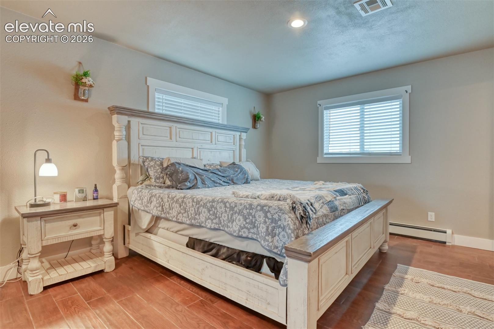 Bedroom with a baseboard heating unit and light wood-style floors