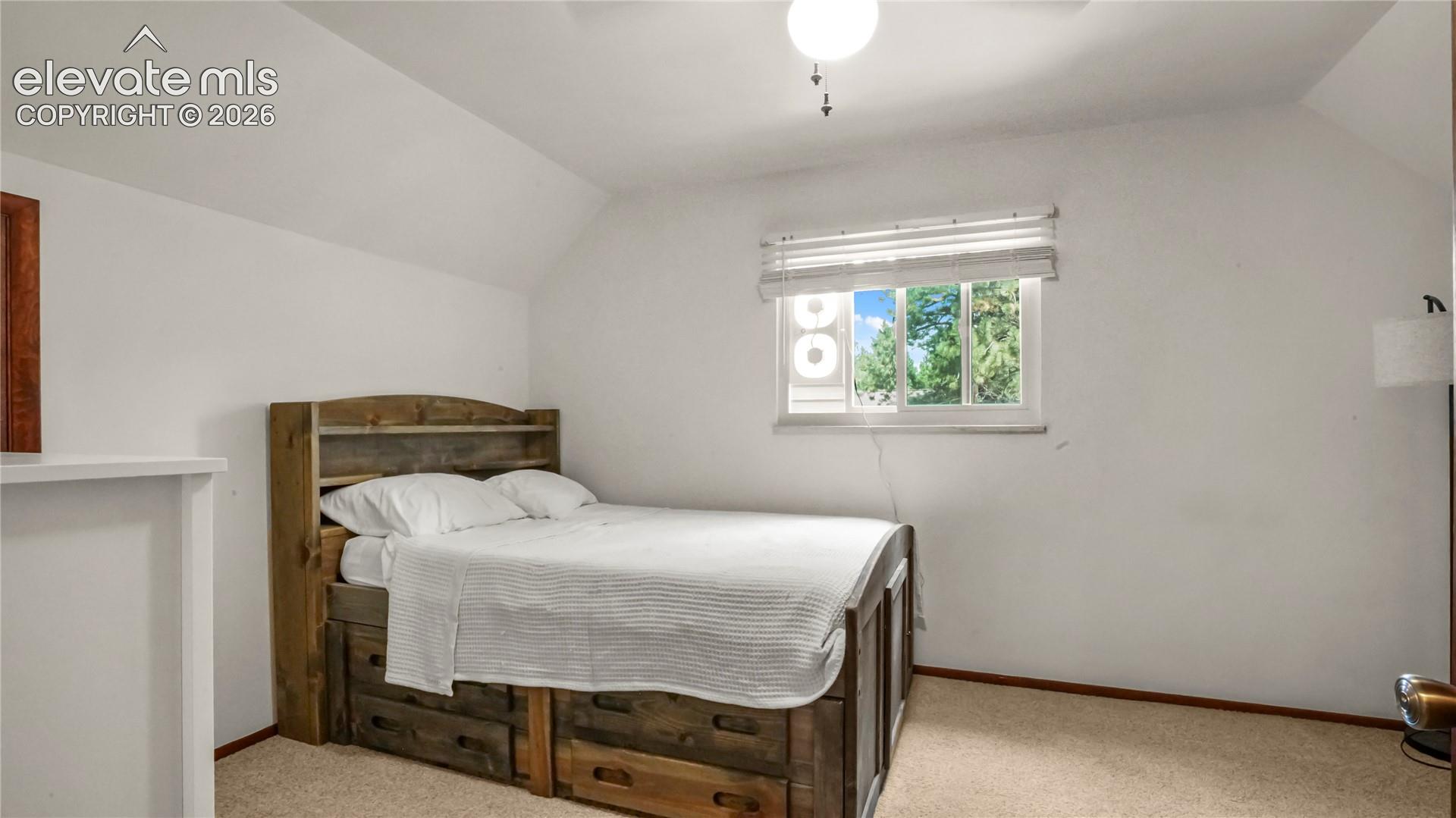 2nd upstairs bedroom, with white walls, sloped ceiling, and a window with blinds. Carpet.