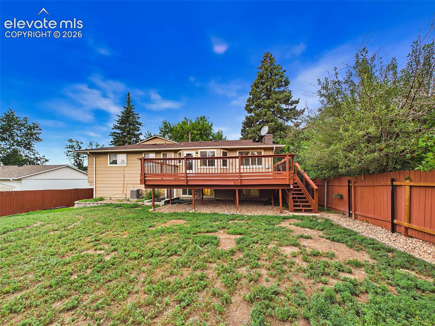 Rear elevation showcases the home's spacious deck, fully fenced backyard, and inviting outdoor living spaces.