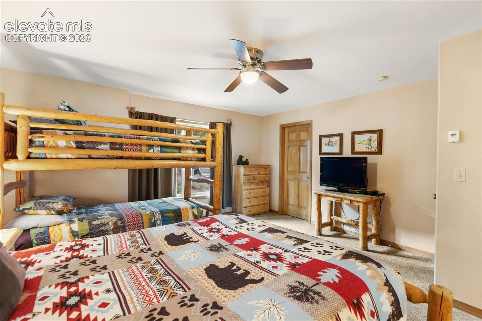 Built-in bunk bed structure, wood-finish interior door, wood-finish dresser, ceiling fan with integrated lighting, and carpeted flooring