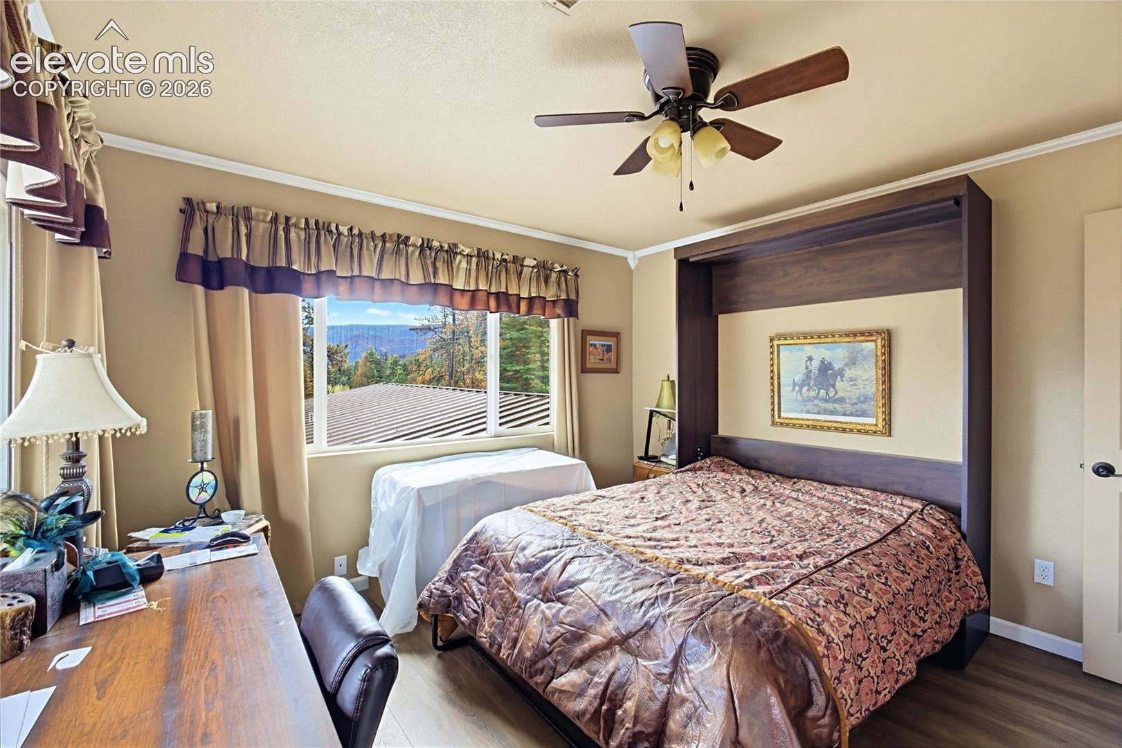 Built-in cabinetry, wood-finish flooring, ceiling fan with integrated lighting, and window featuring mountain scenery