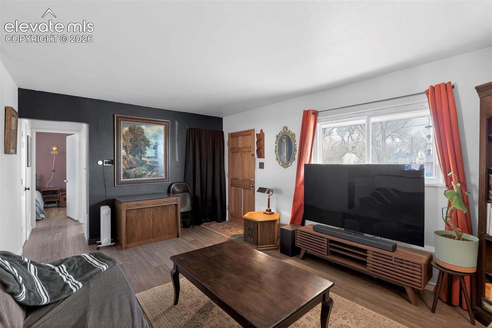 Wood-finish flooring throughout, a white ceiling, and a prominent window