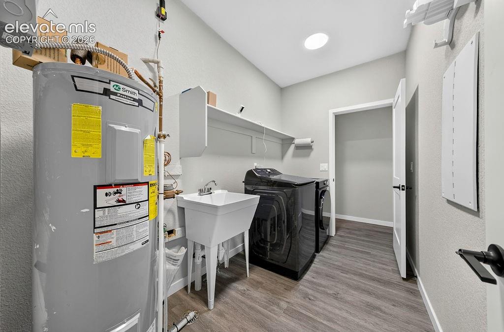 Dedicated utility room featuring a utility sink, wall-mounted shelving, and wood-finish flooring