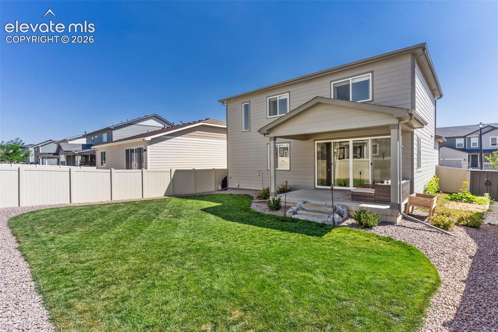 Expansive backyard featuring a manicured lawn, a gravel pathway, and a privacy fence