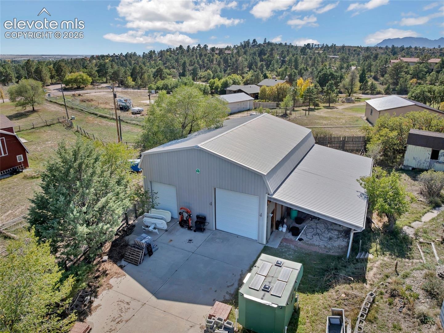 Metal structure with dual garage doors, covered lean-to, and substantial concrete pad