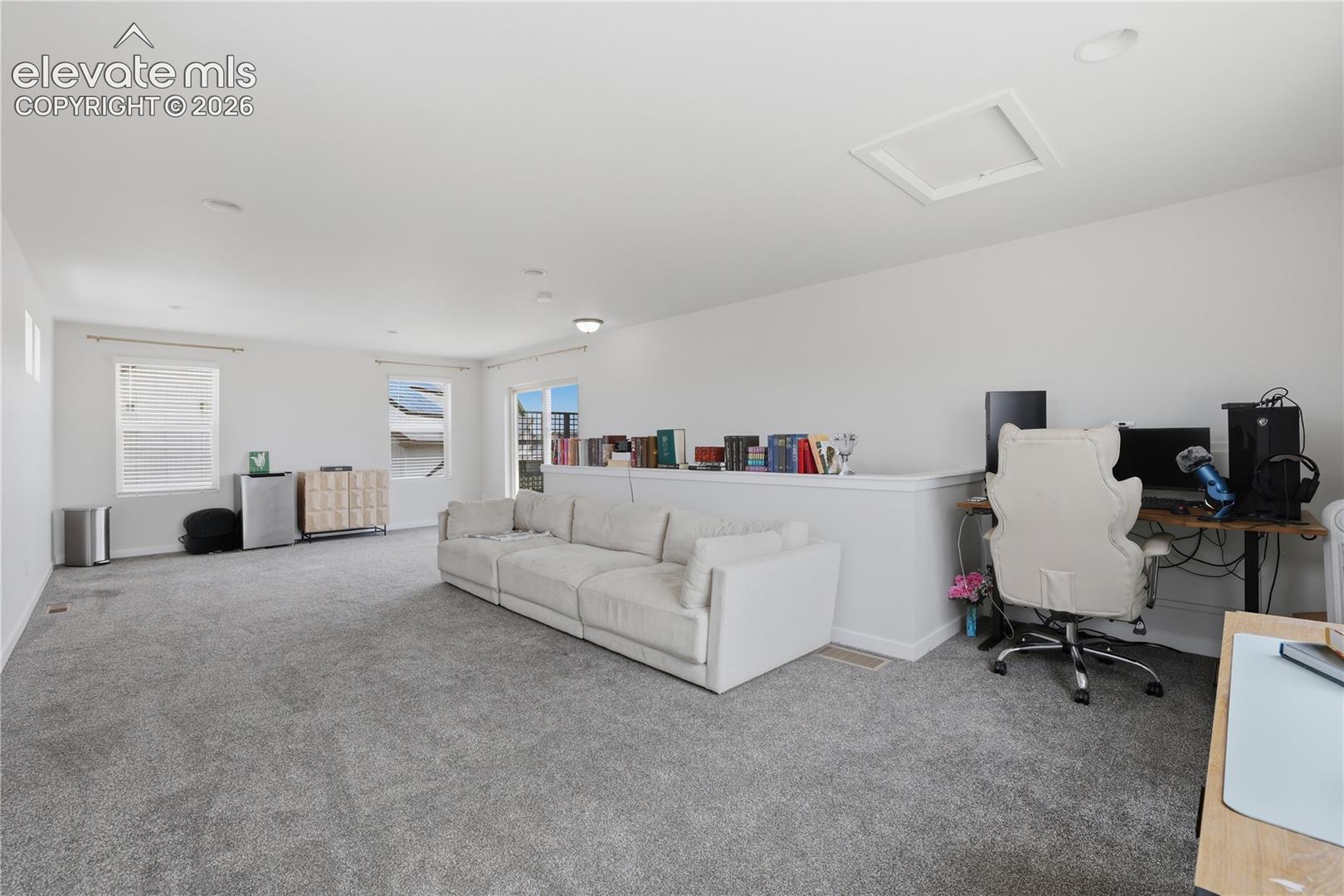Spacious carpeted room featuring multiple windows, a half-wall partition, and white painted walls
