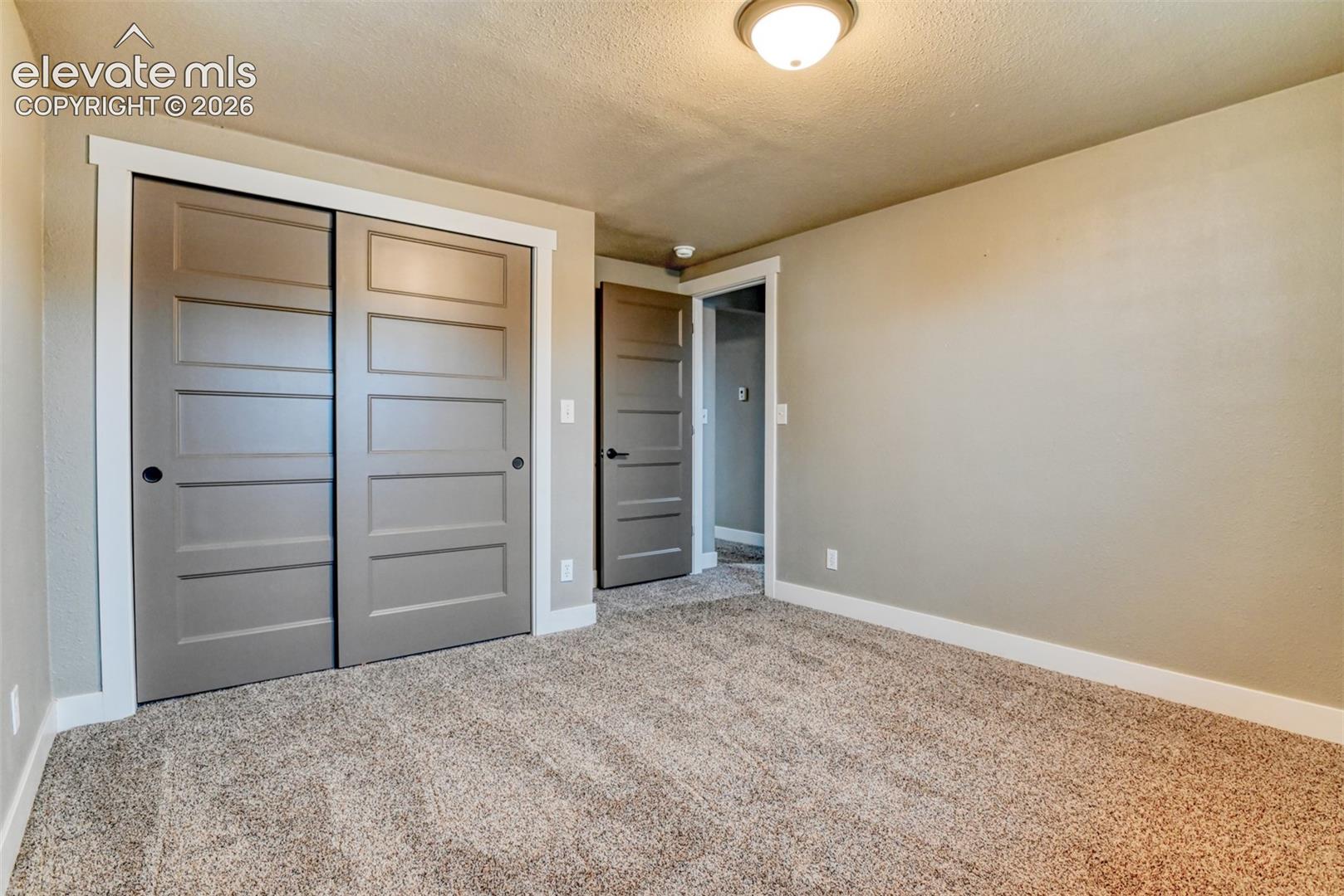 Unfurnished bedroom featuring a closet, light colored carpet, and a textured ceiling