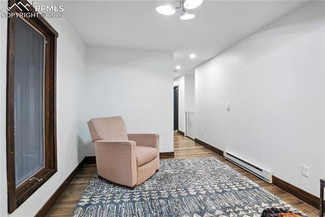 Living area with baseboard heating, wood finished floors, and recessed lighting