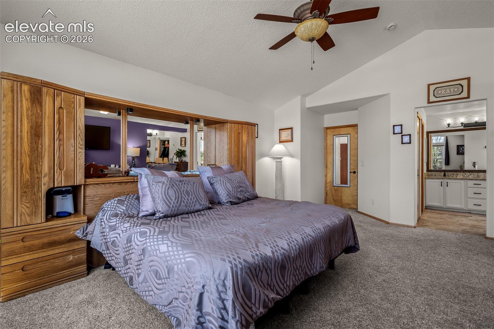 Primary bedroom with aulted ceiling with a ceiling fan.