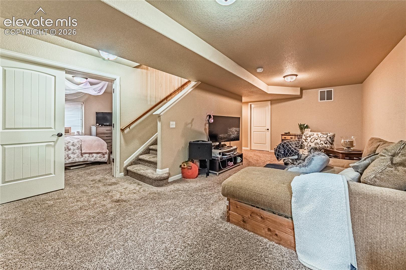 Carpeted living room featuring stairway and a textured ceiling