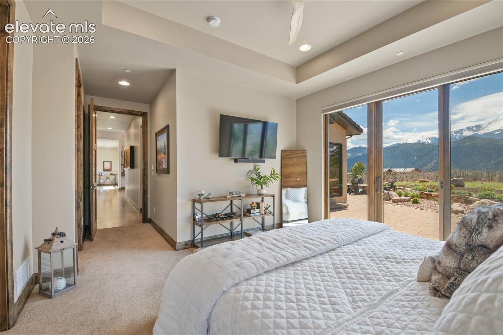 Wake up, slide the door open, and step right onto the patio. Refined main-level junior suite featuring a recessed ceiling detail, integrated TV and sound, sliding glass doors to the backyard retreat, and Pikes Peak as the daily backdrop.