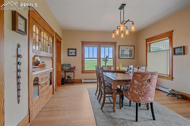 Dining room featuring light wood finished floors, a baseboard radiator, and a chandelier