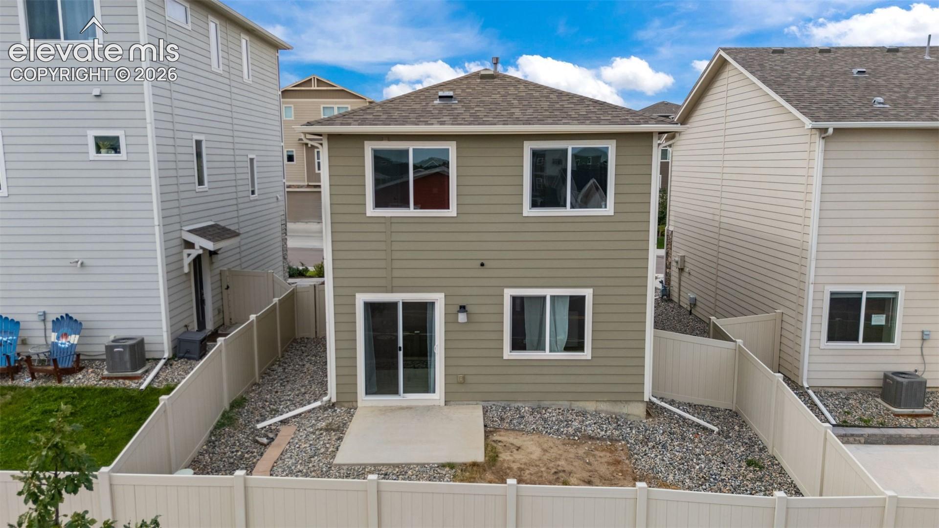 Two-story residence with a tan siding exterior, multiple windows, and a sliding glass door