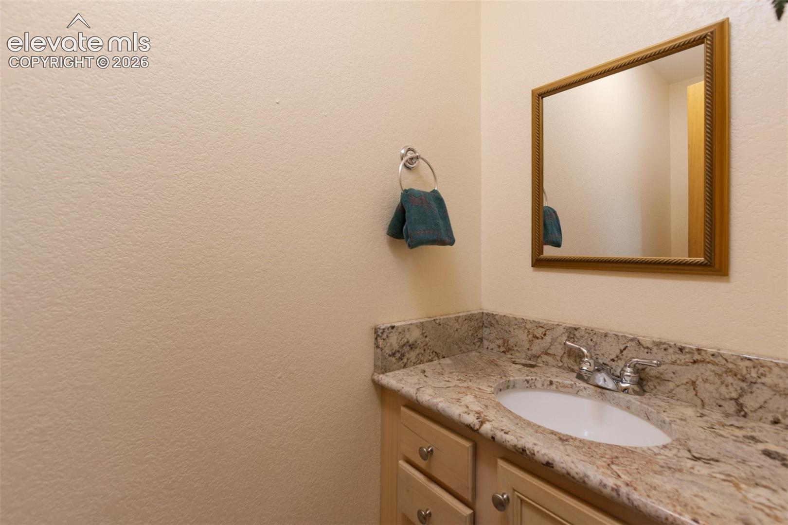Built-in vanity with light-toned cabinetry, an integrated sink, and a speckled countertop
