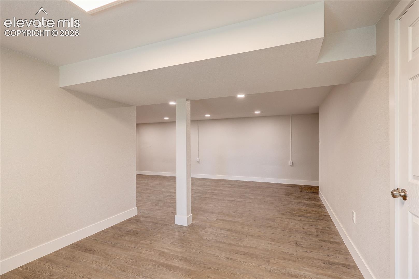 Open-concept interior featuring wood-finish flooring, neutral walls, recessed lighting, and a support column
