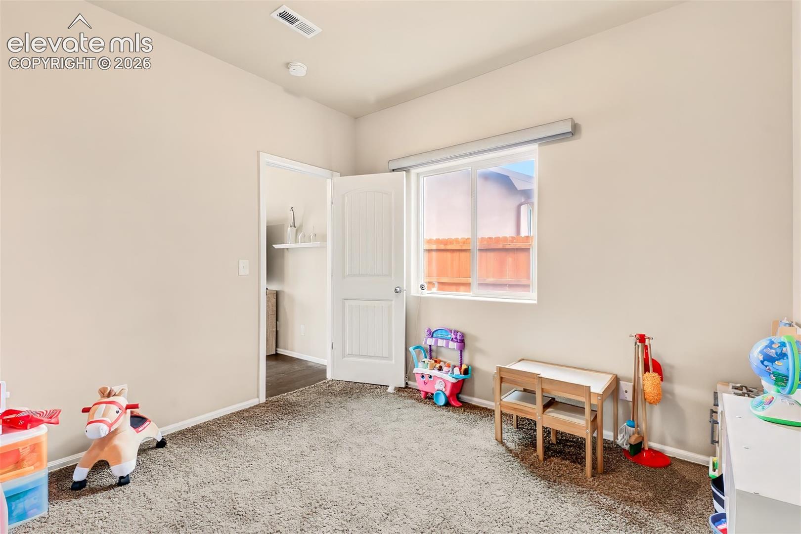 Neutral-toned room featuring neutral carpeting, a single-pane sliding window, and a white two-panel interior door