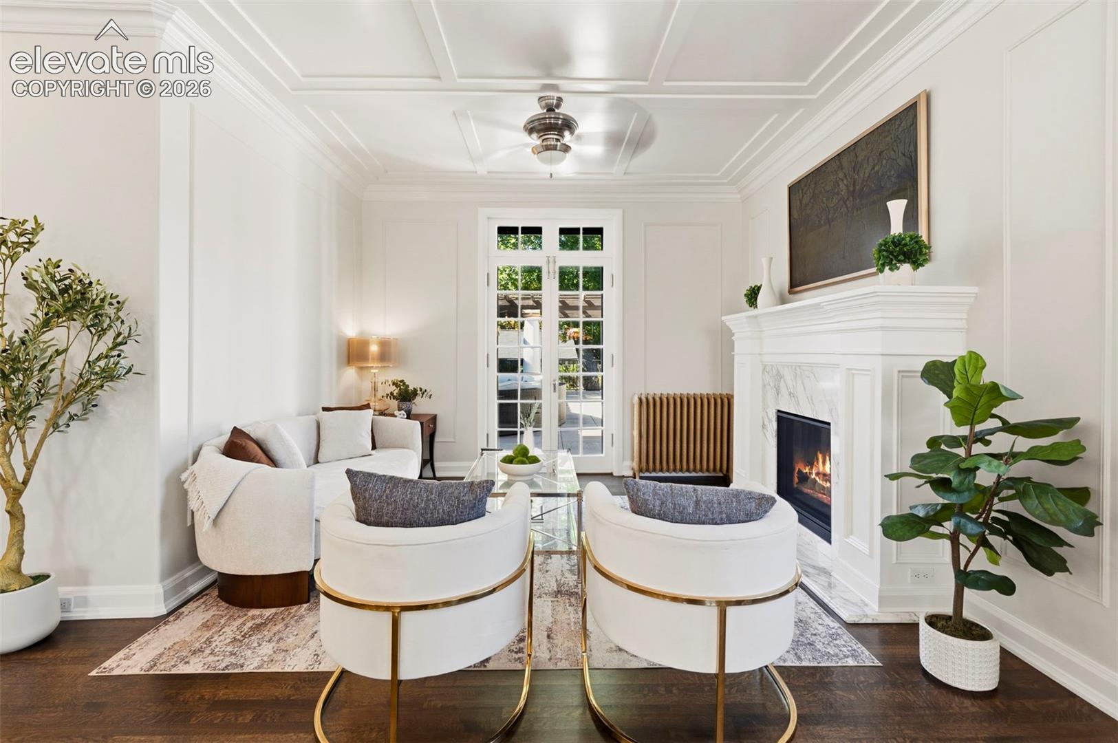 Coffered ceiling with integrated central lighting, fireplace with stone surround and mantle, and multi-light French doors