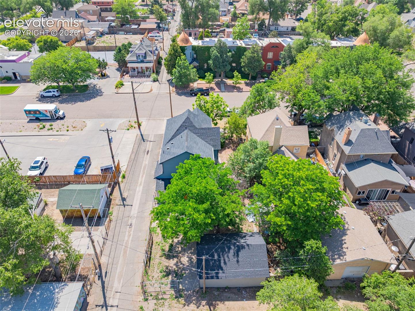 Aerial perspective showcasing a residential property with a dark shingle roof and light gray siding