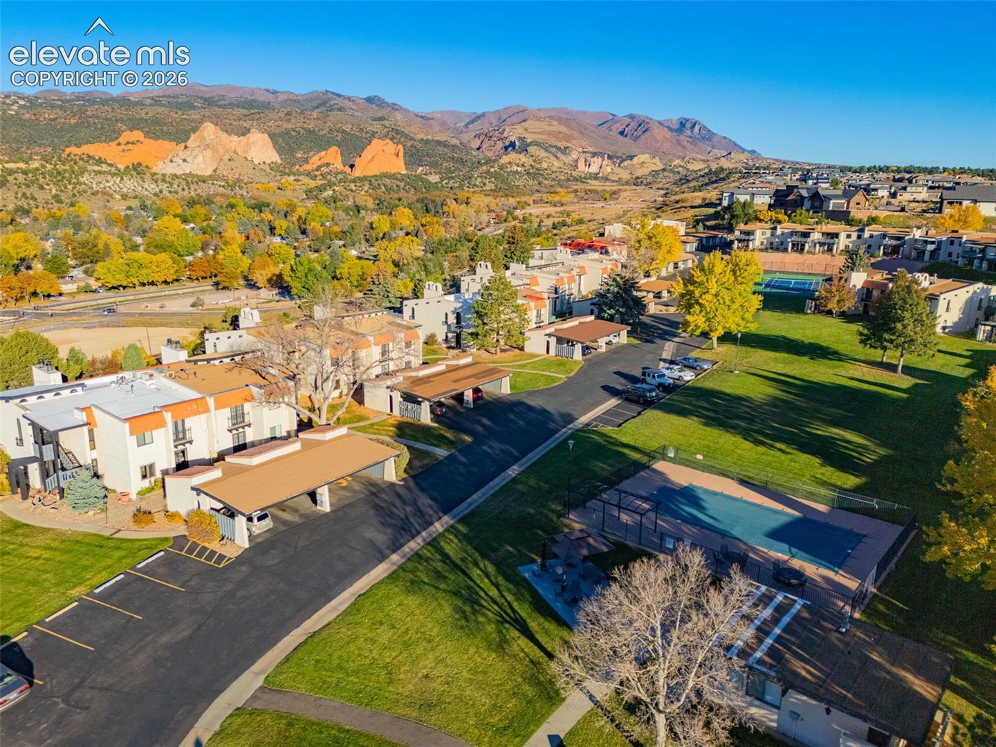 Community grounds featuring a tennis court, a covered swimming pool, covered parking structures, and mature landscaping