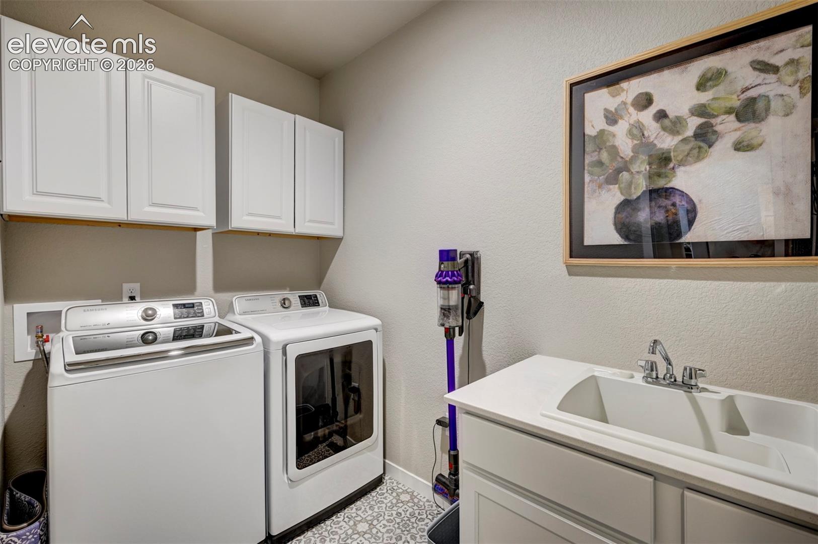 White cabinetry, patterned floor tiling, utility sink, and a built-in countertop