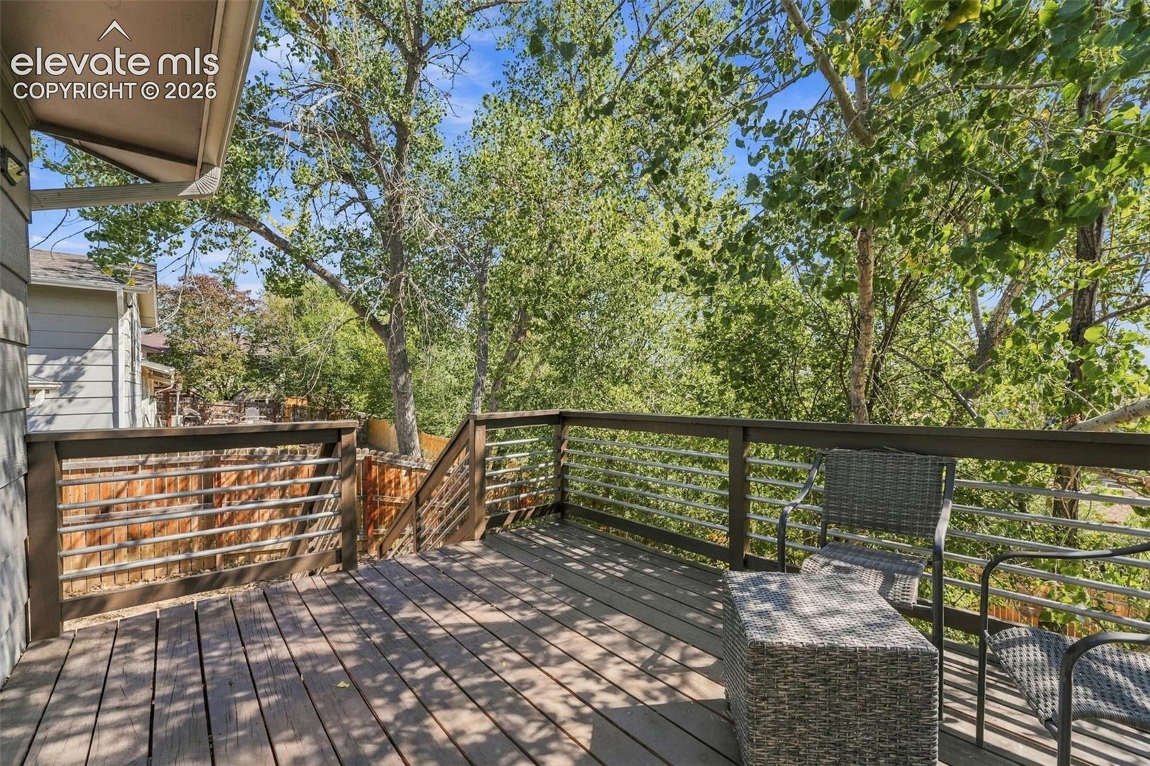 Expansive wood deck with a dark wood railing and horizontal metal balusters, offering an open-air extension of the living space