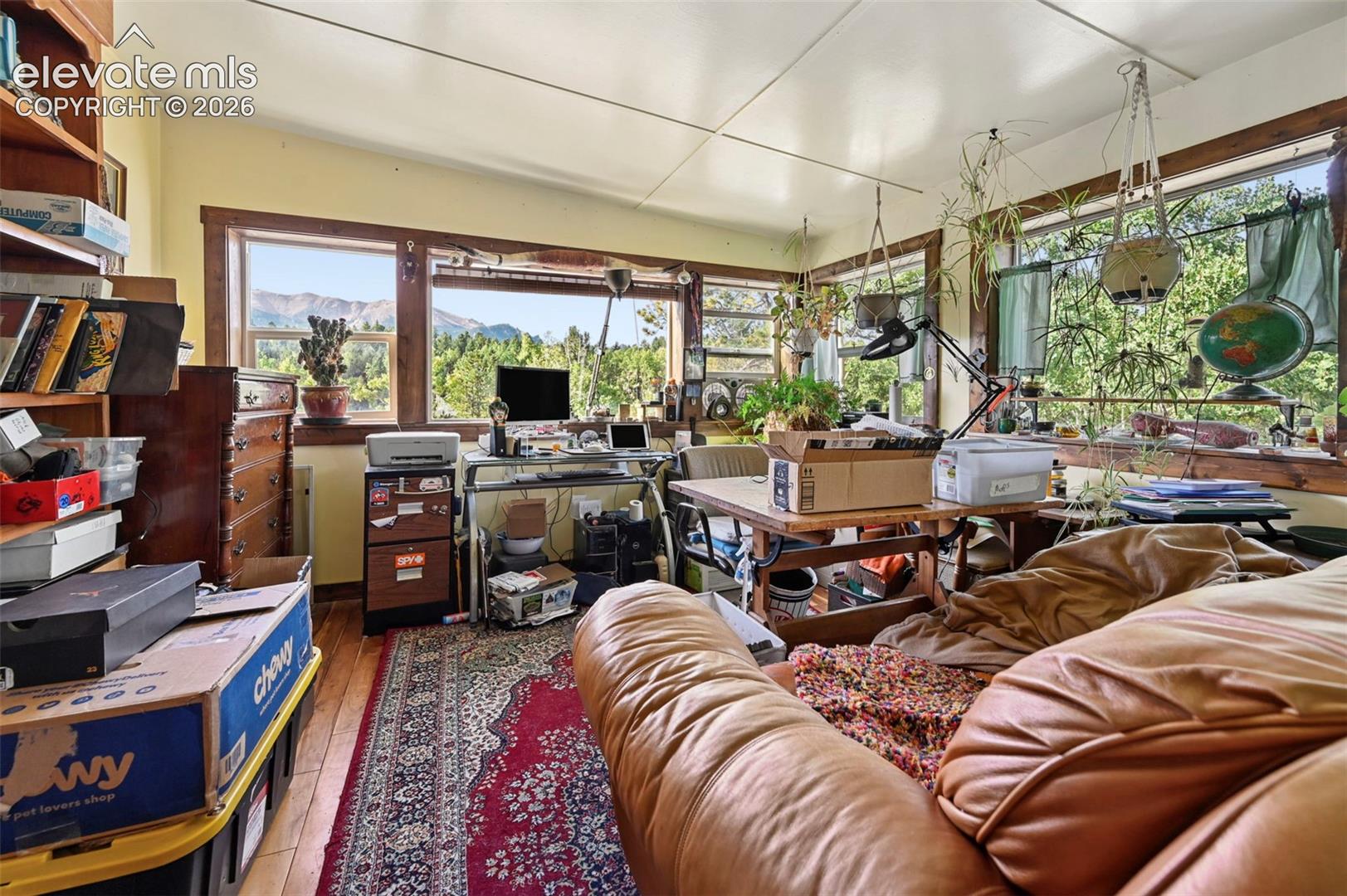 Hardwood flooring throughout, multiple windows, natural wood window trim, built-in shelving, and exposed ceiling beams