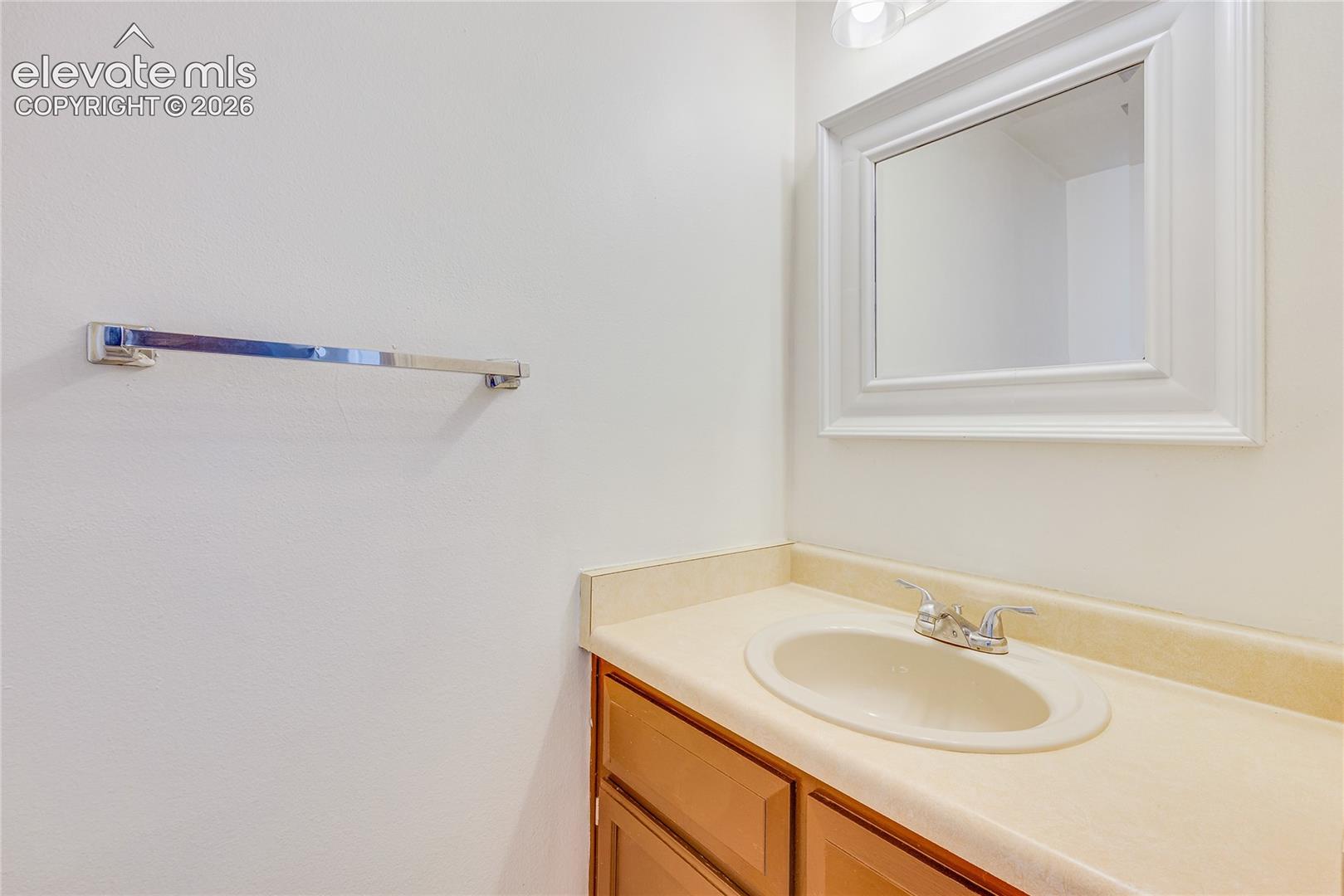 Vanity with an integrated sink, dual-handle faucet, wood-finish cabinetry, and a framed mirror