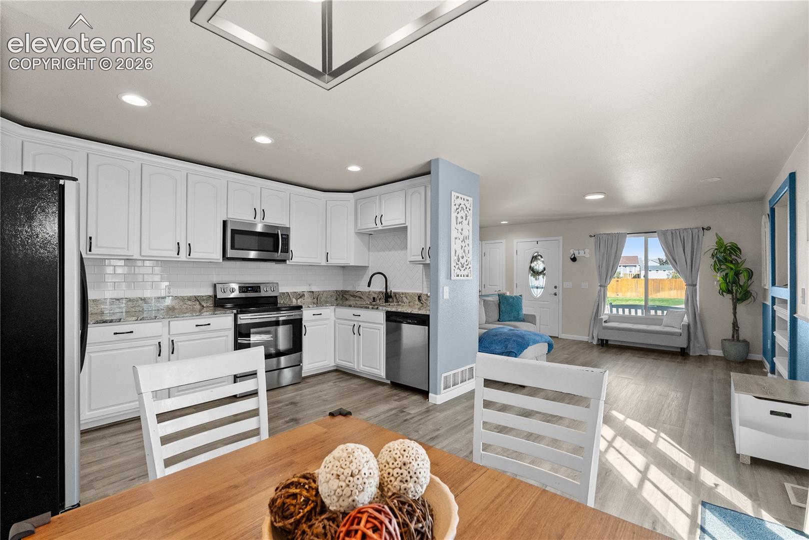 Kitchen featuring white cabinetry, stainless steel appliances, a tile backsplash, and light-toned countertops