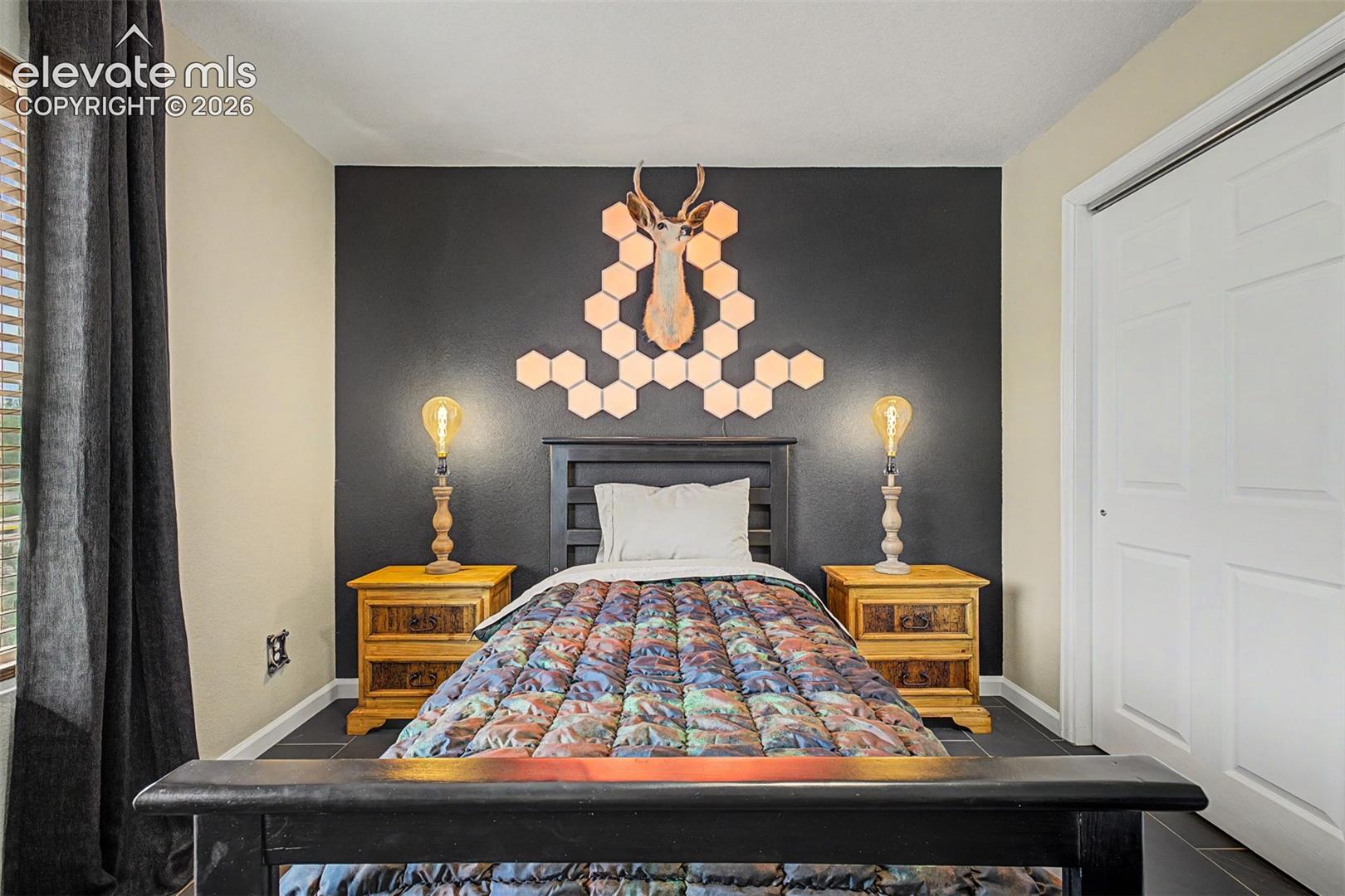 This main level secondary bedroom makes a bold design statement with a dramatic charcoal accent wall and custom lighting, proving that every room in this home has been given its own distinct identity.