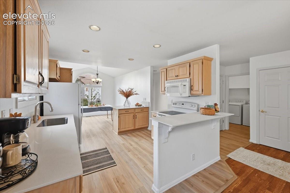 Kitchen featuring light-finish cabinetry, white solid-surface countertops, recessed lighting, and wood-finish flooring