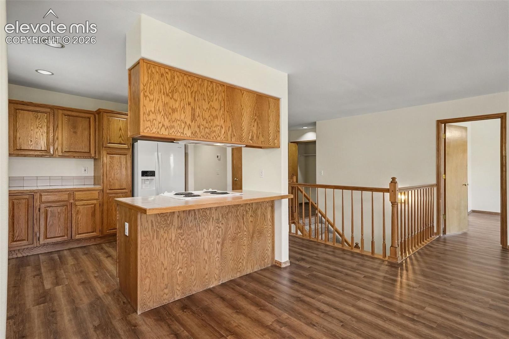 Kitchen with new LVP flooring, built-in cabinetry, white appliances, and a breakfast bar