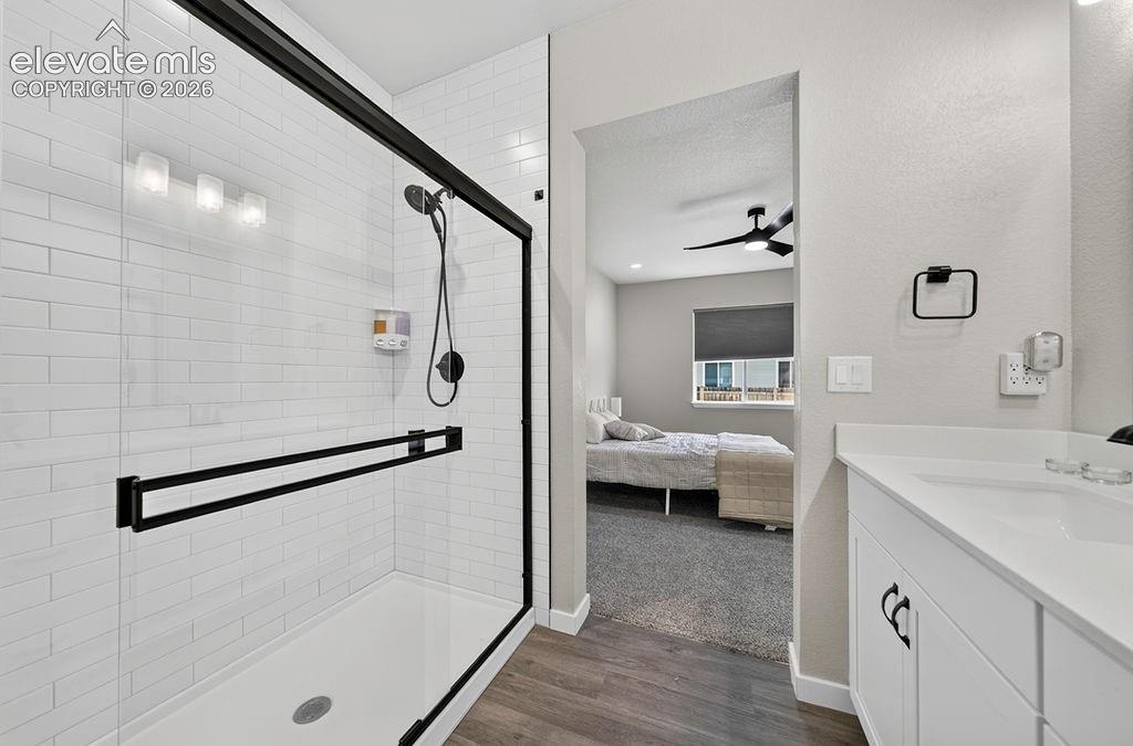 Bathroom featuring a glass-enclosed shower with subway tile surround, matte black shower fixtures, and a white vanity with integrated sink