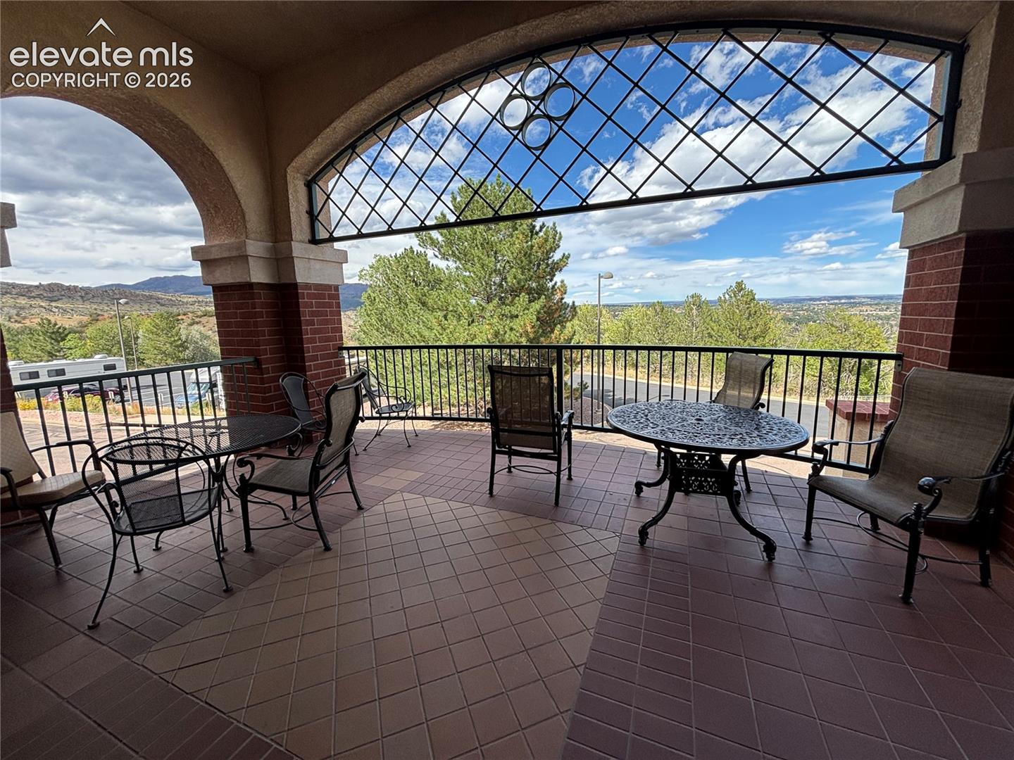 Covered patio featuring an arched entryway and brick columns