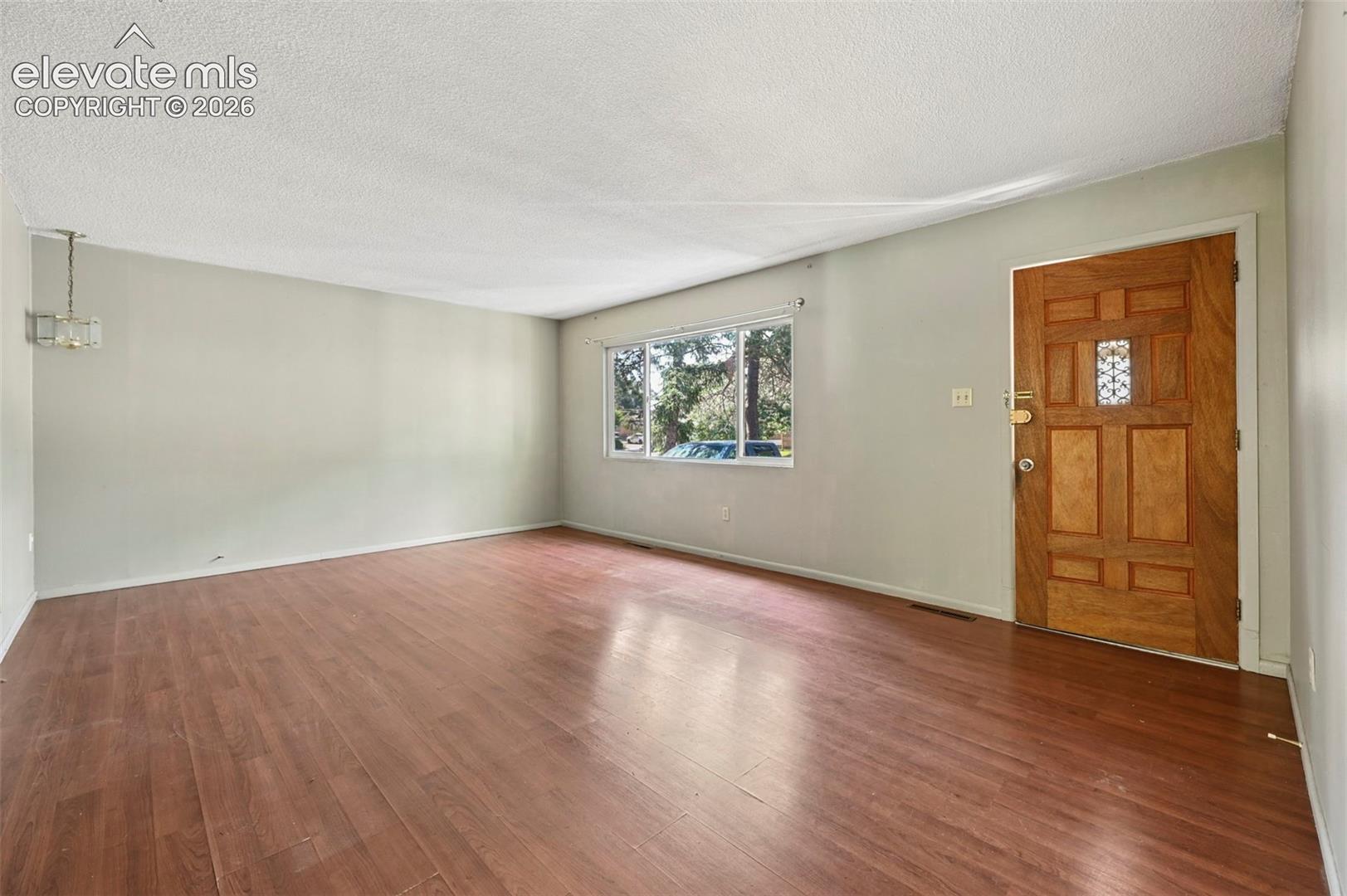 Open living space featuring wood-finish flooring and a front entry door with a decorative glass insert