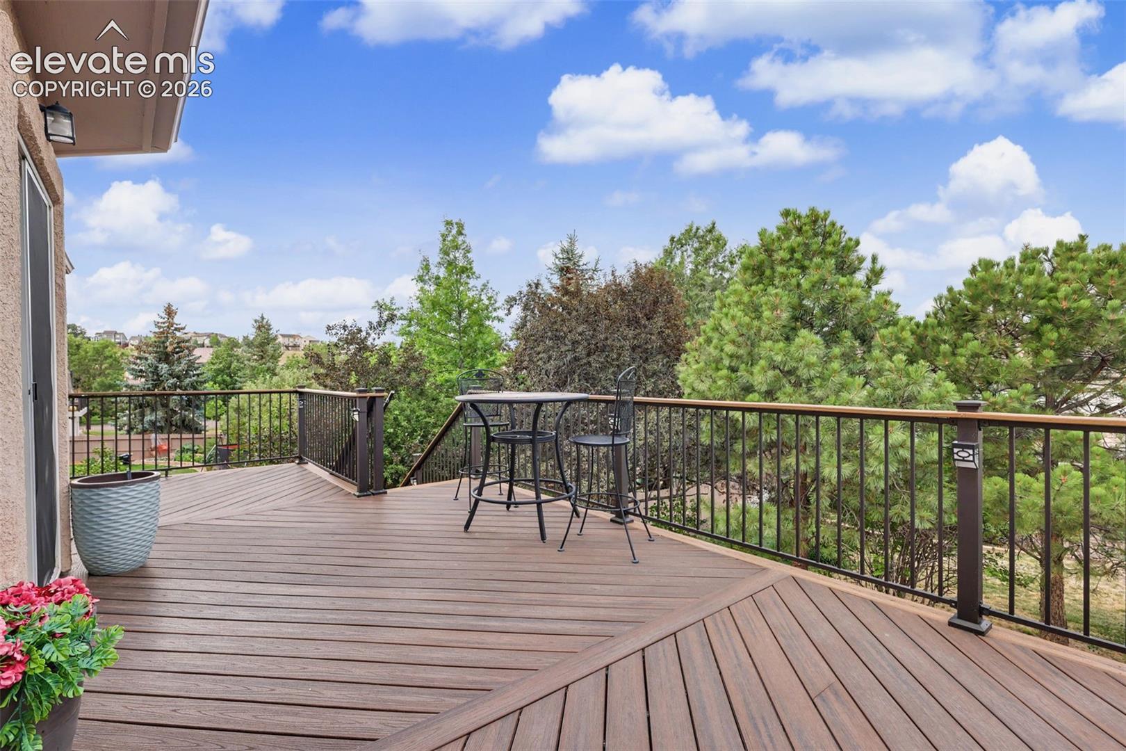 Spacious deck featuring composite decking, dark metal railings, and a natural tree-lined backdrop