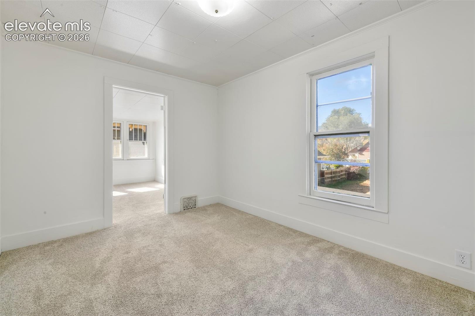 Neutral-toned carpeted flooring, white wall finishes, crisp casing around window and door frames, and a multi-pane window