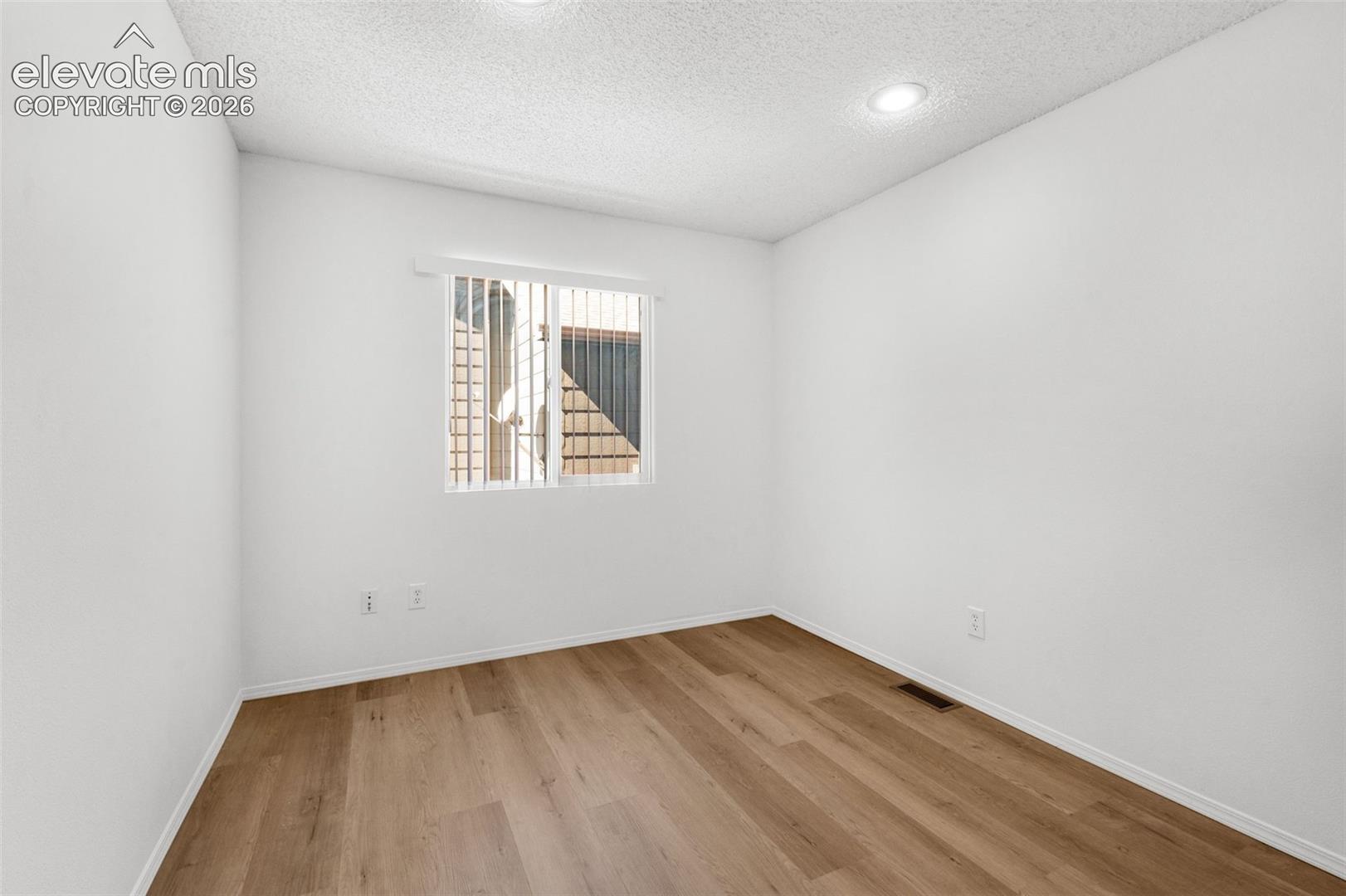 Recessed lighting fixtures, window with vertical blinds, wood-finish flooring, and crisp white walls