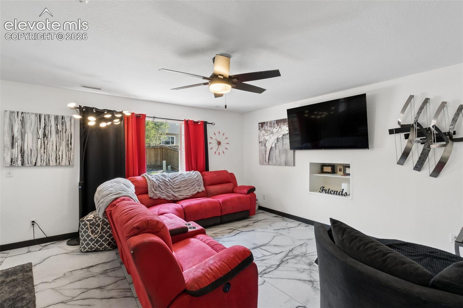 Living area featuring a ceiling fan, recessed niche, and tile flooring
