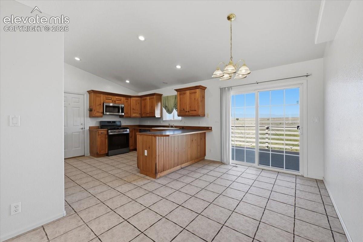 Kitchen featuring wood cabinetry, stainless steel microwave, black range, and a two-tier kitchen island with beadboard paneling