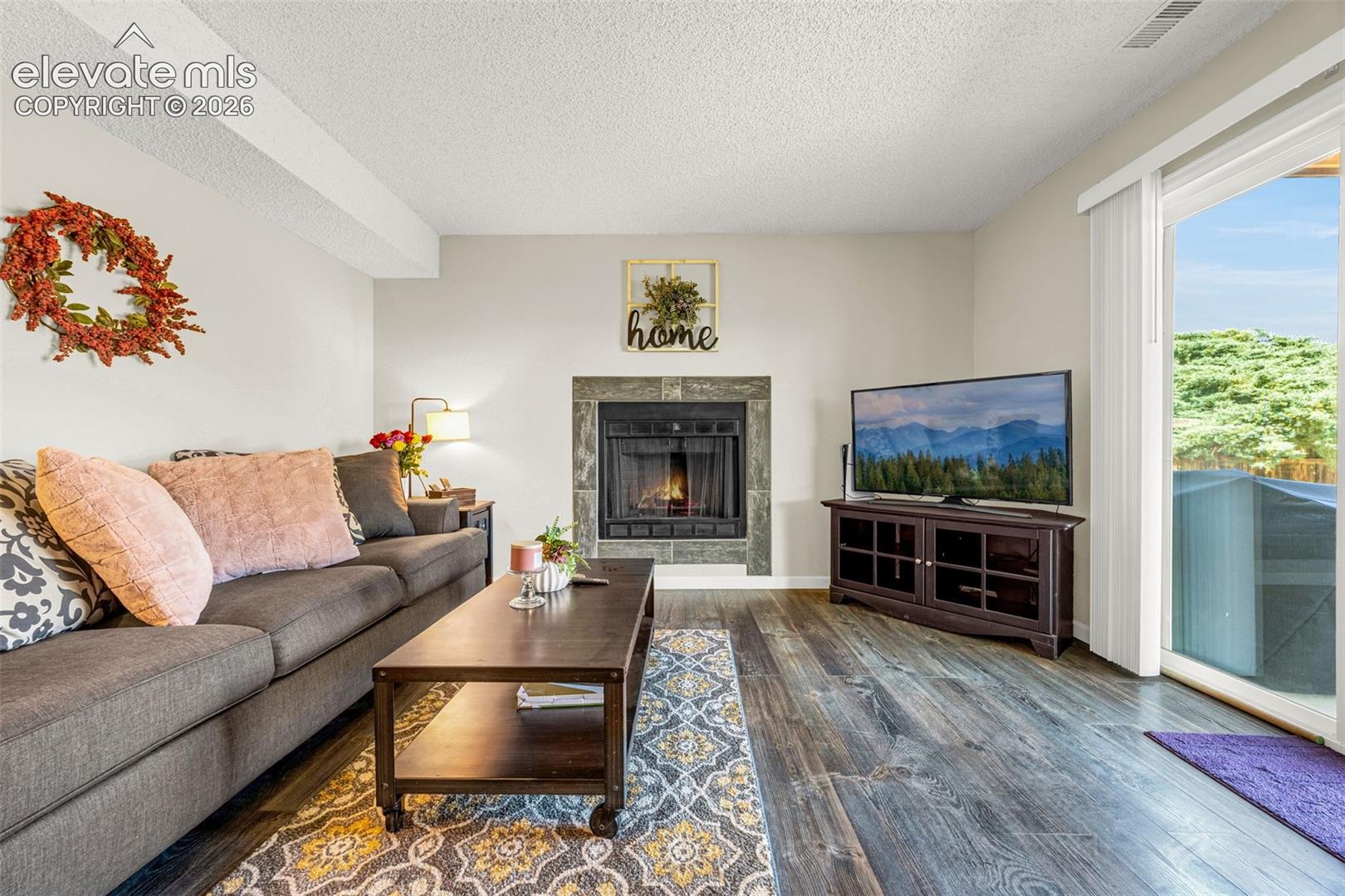 Wood-finish flooring, stone-surround fireplace, and sliding glass door with exterior access